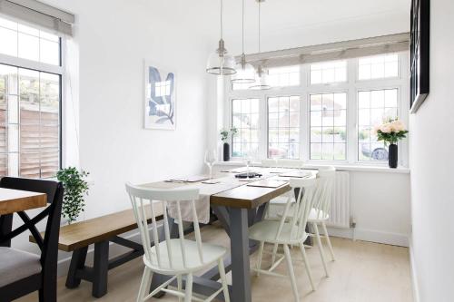 a dining room with a table and white chairs at Bright & Modern 4 br House 100 metres from Beach in West Wittering