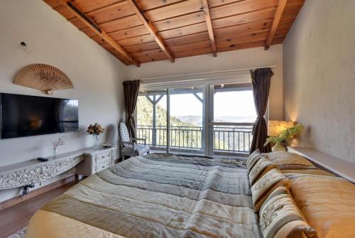 マックトシュワーにある2Bhk Home By Da Alohas Mukhteshwarの大きなベッドと大きな窓のある寝室