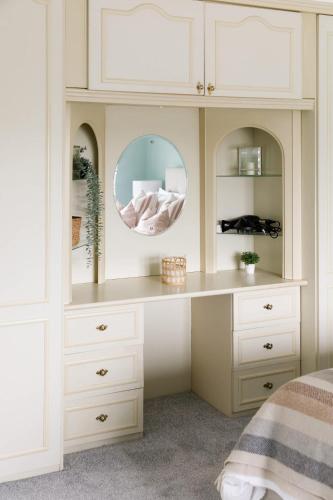 a white hutch with a mirror in a bedroom at Bright & Modern 4 br House 100 metres from Beach in West Wittering