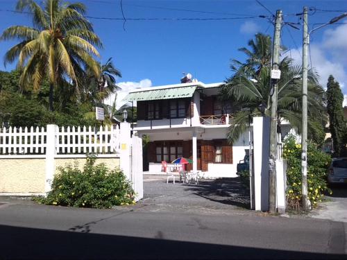 a white house with a white fence and a palm tree at Auberge Etiennette in Trou dʼ Eau Douce