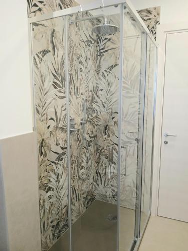a shower stall in a bathroom with a floral wallpaper at OASI appartamento in Cannobio