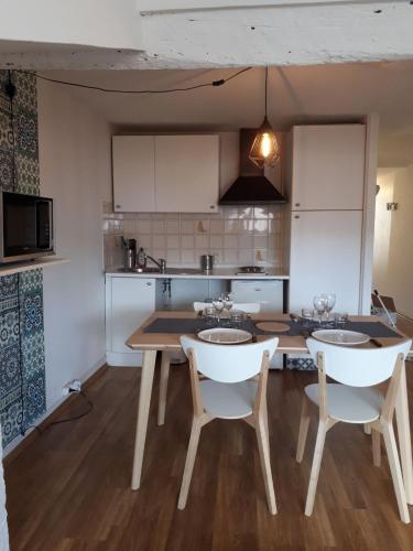 une cuisine avec une table et deux chaises et une cuisine avec des placards blancs dans l'établissement 2 pièces Petit Bayonne, à Bayonne