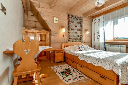 a bedroom in a log cabin with a bed and a chair at U Pabinów in Kościelisko