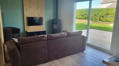 - un salon avec un canapé brun et une porte coulissante en verre dans l'établissement Maison le dauphin Kerlouan, à Kerlouan