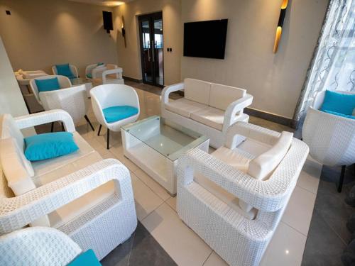 a living room with white chairs and a tv at Tripod By Pedestal Hotel in Owerri