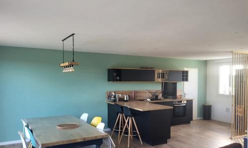 une cuisine avec une table et un mur bleu dans l'établissement Maison le dauphin Kerlouan, à Kerlouan