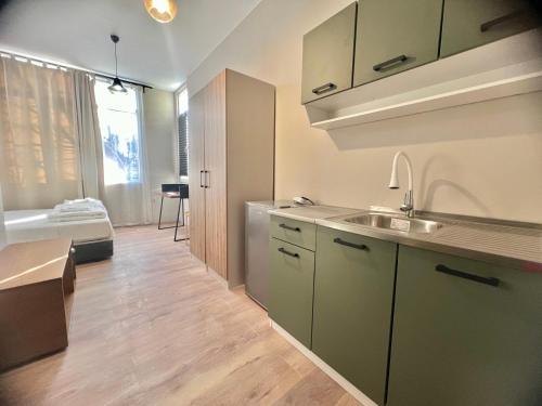 a kitchen with a sink and a room with a bed at Just Home in Varna City