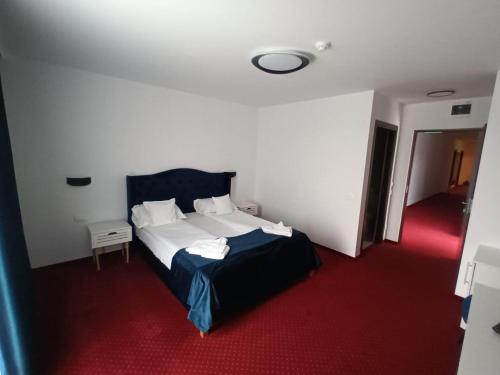 a bedroom with a white bed and a red carpet at Hotel Transilvania Zalău in Zalău