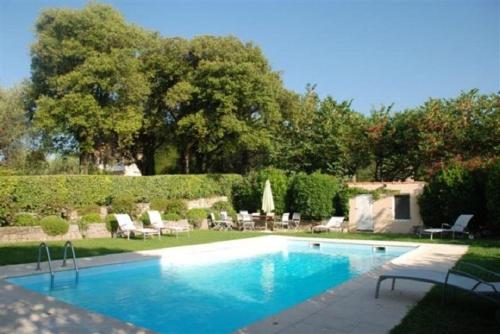 une piscine dans une cour avec des chaises et des tables dans l'établissement Mouans Sartoux, bastide avec magnifique parc et piscine, à Mouans-Sartoux