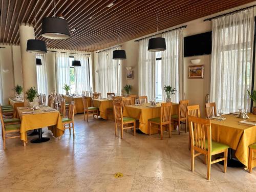 a dining room with tables and chairs and windows at Casa Vlasia in Snagov