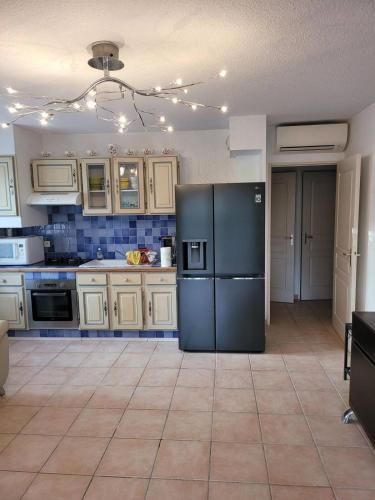 Il comprend une cuisine équipée d'un réfrigérateur noir et de placards blancs. dans l'établissement Un coin de paradis, à La Londe-les-Maures