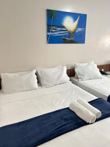 a bedroom with two beds and a painting on the wall at Nautillus Hotel in Parnaíba