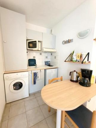 une petite cuisine avec une table et un lave-linge. dans l'établissement Le Coin du Curiste - Port de Plaisance, à Rochefort