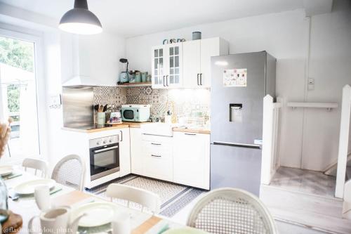 - une cuisine avec des appareils blancs, une table et des chaises dans l'établissement La Belle Longère, havre de paix 3 étoiles face aux vignes, à Trelou Sur Marne