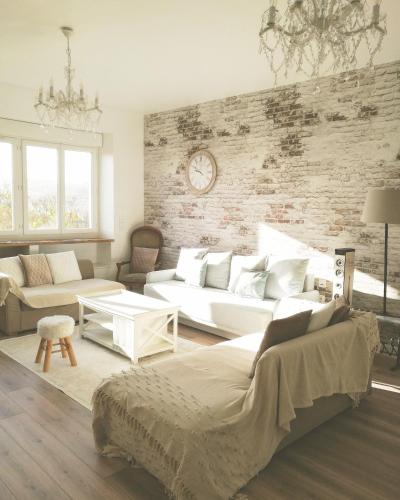 Il comprend un salon doté d'un mobilier blanc et d'un mur en briques. dans l'établissement La Belle Longère, havre de paix 3 étoiles face aux vignes, à Trelou Sur Marne