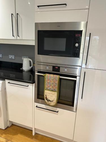 a kitchen with a stainless steel oven with a microwave at Together in Ealing, Modern Two Bedroom Flat with Garden, Patio, Parking and Sleeps Five in Ealing