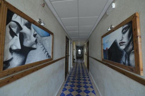 a hallway with black and white pictures on the walls at Hotel des Oudaias in Rabat