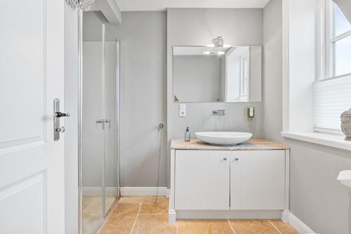 Un baño blanco con lavabo y espejo. en Reetdachhaus Reetkoje Reetdachhaus Reetkoje II, en Süderhöft