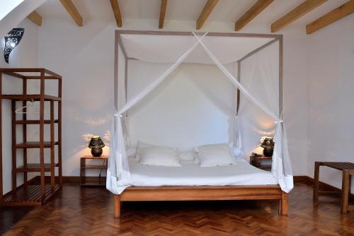 a bedroom with a canopy bed with white pillows at Riviera Garden in Antananarivo