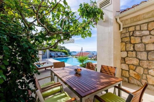a patio with a wooden table and chairs and a pool at Elegant Sea-View Villa with Pool in Mlini