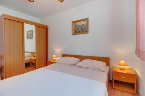 a bedroom with a white bed and two night stands at Apartments Anci in Mali Lošinj