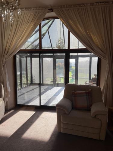 a living room with a couch in front of a large window at The Stables East Lodge Country House in Great Rowsley