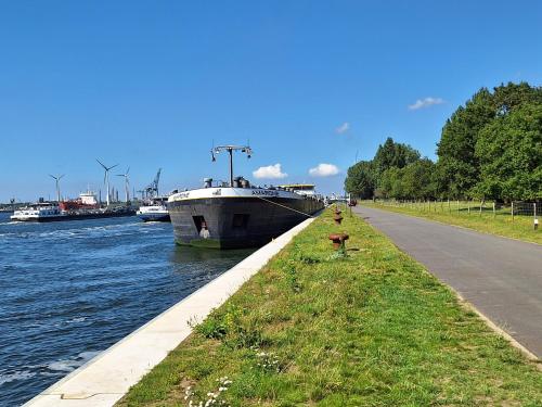 a boat is docked on a river with a grass median at Polderzicht in Ossendrecht