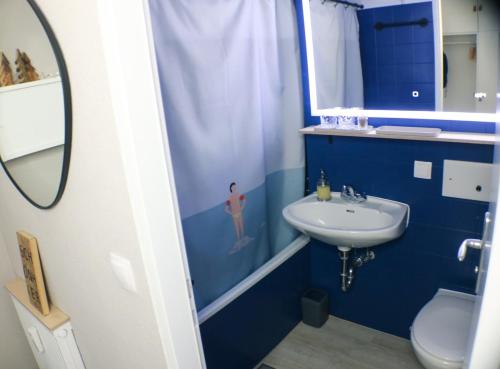 a blue bathroom with a sink and a toilet at Schönhier - Design Apartment mit Pool, Sauna in Schluchsee