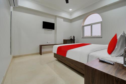 a bedroom with a bed with red pillows and a tv at Hotel O Shiv Mahima in Jaipur