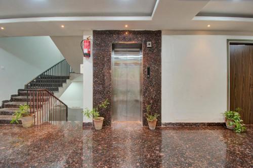 a lobby with a door and stairs with potted plants at Hotel O Shiv Mahima in Jaipur