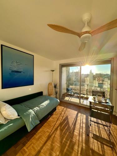 une chambre avec un lit et un ventilateur de plafond dans l'établissement Mobility lease- Sunny studio with large balcony, park view at Paris 15, à Paris