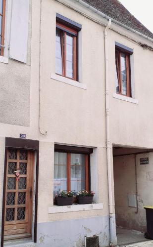 a building with two windows and two potted plants at Escale de Cravant in Deux-rivières