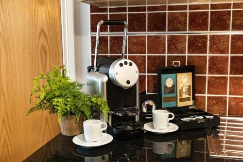 a kitchen counter with cups and a coffee machine at Lahinch Coast Hotel and Suites in Lahinch