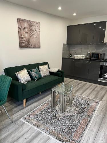 a living room with a green couch and a table at Guest house in london in Edgware