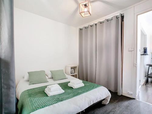 une chambre blanche avec un lit avec des serviettes dessus dans l'établissement Apartment Grignard, à Cherbourg en Cotentin