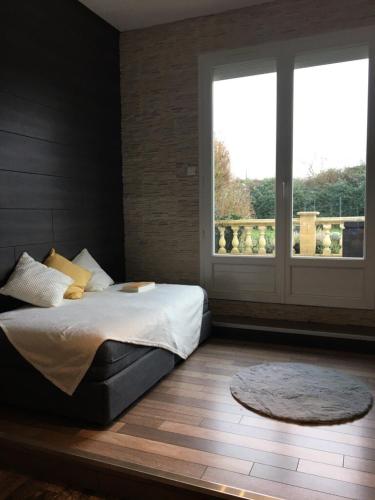 une chambre avec un lit et une grande fenêtre dans l'établissement La Canopée - Villa familiale avec piscine chauffée, à Saint-Philbert-sur-Risle