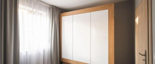 a bedroom with a large white cabinet and a window at Apartamenty Forma Tatrica in Zakopane