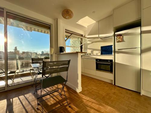 une cuisine avec un comptoir, une table et une fenêtre dans l'établissement Mobility lease- Sunny studio with large balcony, park view at Paris 15, à Paris