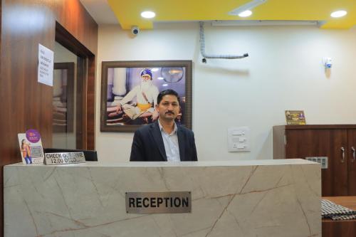 a man standing behind a reception counter in an office at Hotel Novelty Inn - 2 min walk from Golden Temple in Amritsar
