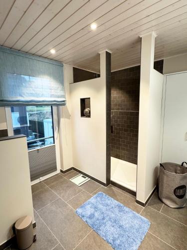a bathroom with a shower and a blue rug at Lille Fjord Hus in Schleswig
