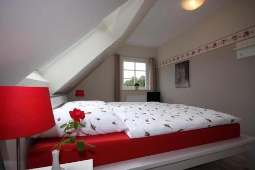 Schlafzimmer mit einem roten und weißen Bett und einem Fenster in der Unterkunft Ferienhaus Uhlenhus in Prerow