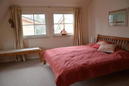 um quarto com uma cama com um cobertor vermelho e uma janela em Hagens Hus em Prerow