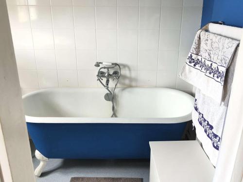 une baignoire bleue et blanche avec un robinet dans une salle de bain dans l'établissement Belle maison à 50m de la plage et proche commerces - FR-1-736-28, à Lège-Cap-Ferret