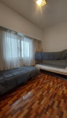 a bedroom with two beds and a wooden floor at Departamento bolivar in Mar del Plata