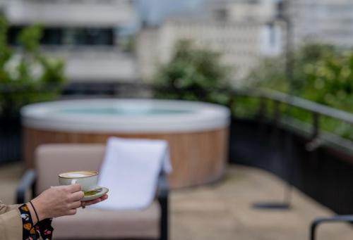 a person holding a cup of coffee on a balcony at FirstName Bordeaux, Part of JdV by Hyatt in Bordeaux