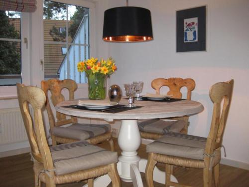 a dining room with a table with chairs and a vase of flowers at Strandlust in Prerow