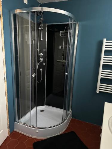 La salle de bains est pourvue d'une douche en verre et d'un mur bleu. dans l'établissement Appartement 2 chambres, à Baix