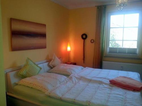 a bedroom with a large white bed with a window at Am Stemsbach in Prerow