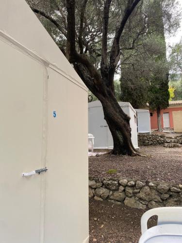 a white garage with a tree next to it at Camping Paleokastritsa in Paleokastritsa
