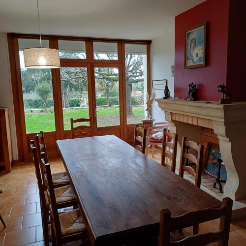 une salle à manger avec une table en bois et une cheminée dans l'établissement Gîte la maison du bonheur, à Montignac-Charente